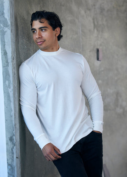 Spun Bamboo long-sleeve crewneck in Cream, shown against a concrete wall.