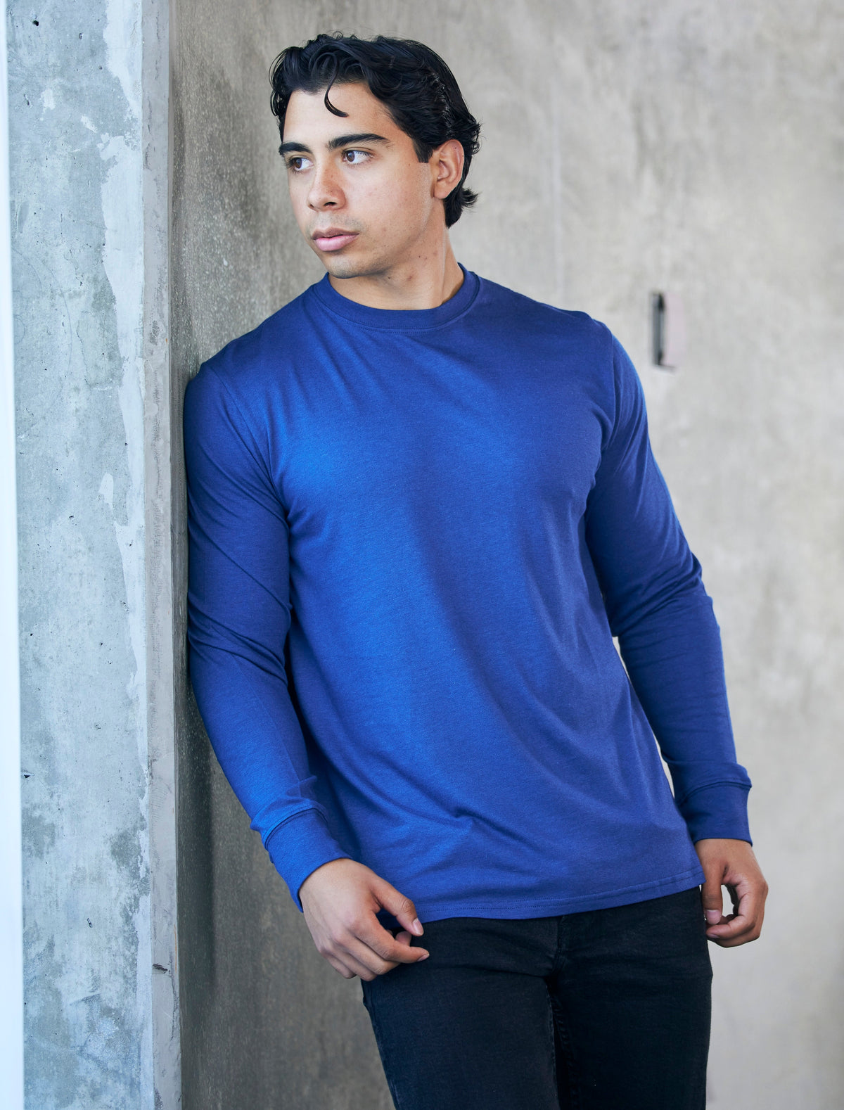 Spun Bamboo long-sleeve crewneck in Royal Blue, shown against a concrete wall.