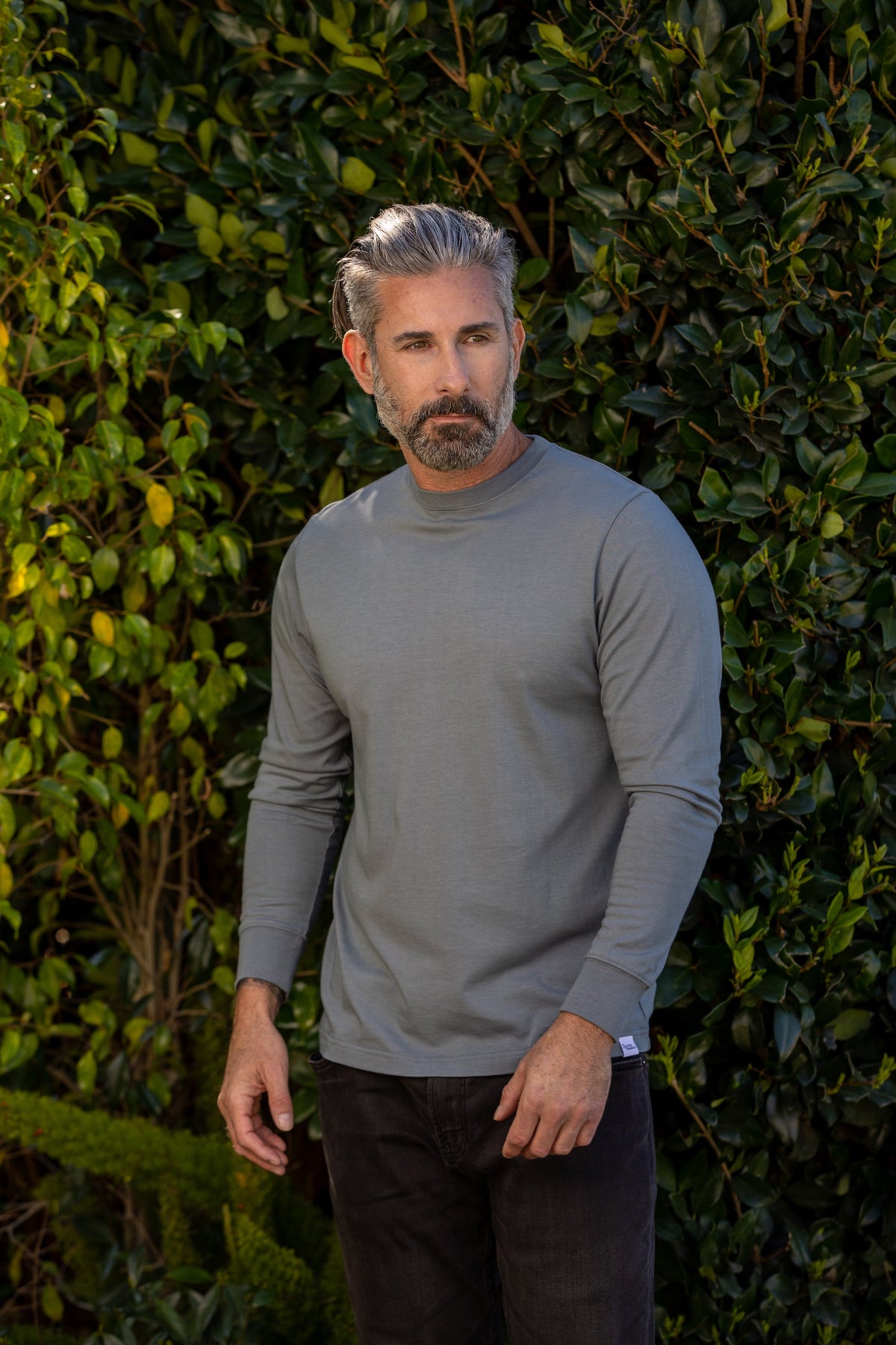 Grey Spun Bamboo long-sleeve crewneck worn outdoors in front of a green hedge.