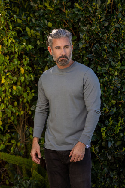 Grey Spun Bamboo long-sleeve crewneck worn outdoors in front of a green hedge.