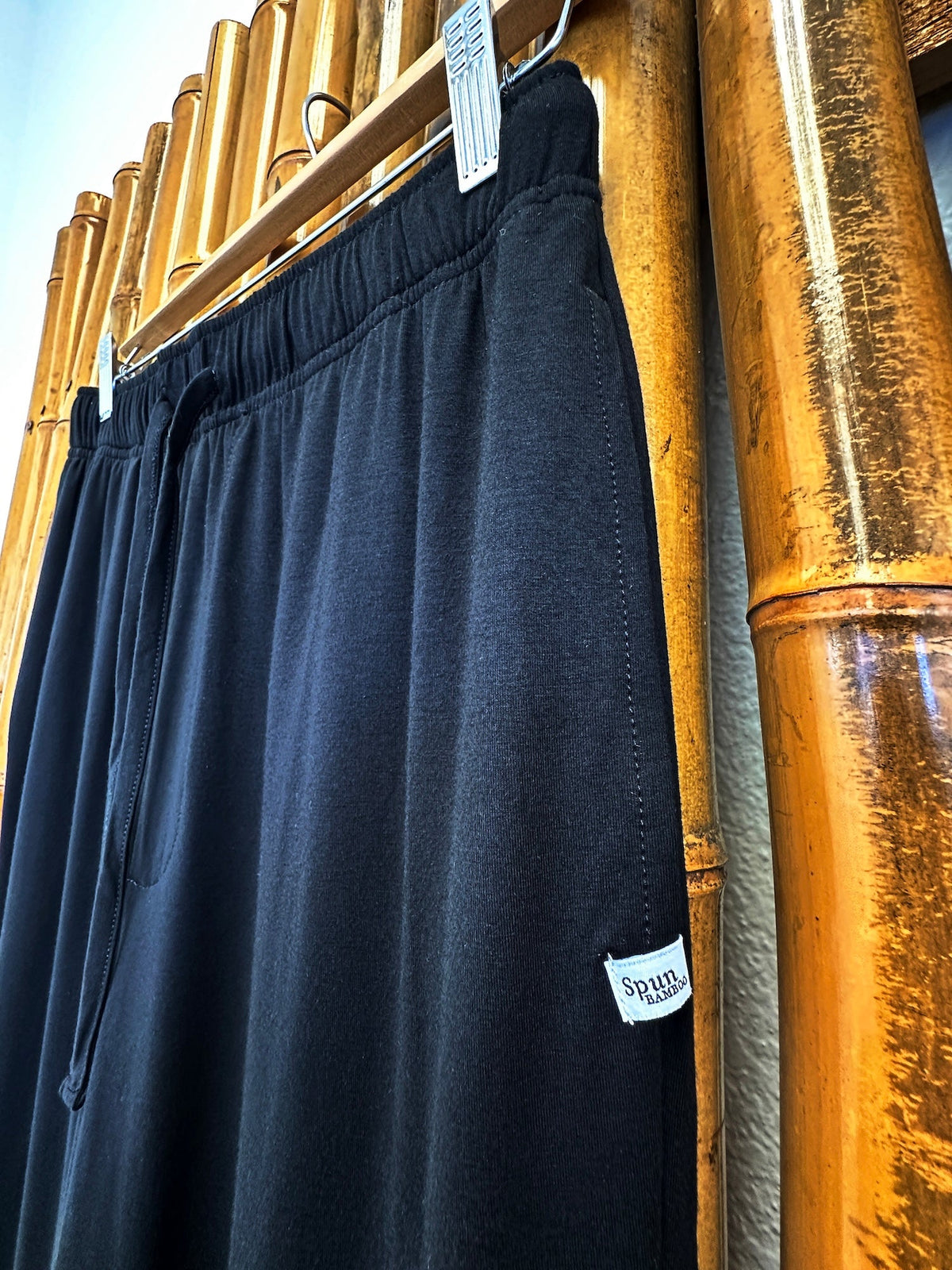 Angled close-up of Black Spun Bamboo lounge pants showing the waistband, fabric and side label.