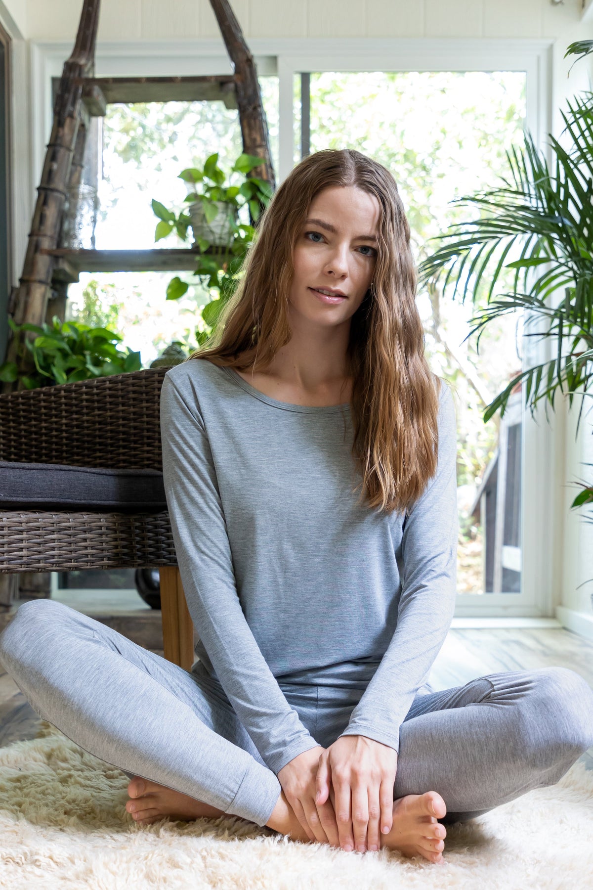 Spun Bamboo women's long-sleeve lounge tee in Heather Grey, seated lifestyle view; trousers not included.